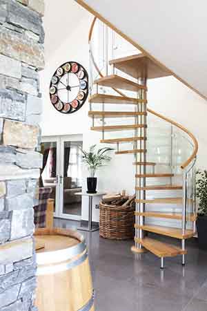 spiral stair with curved glass panels and oak tread with a clock on the wall