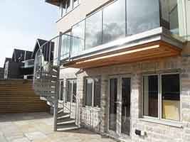 glass balustrade on an outside balcony of a house with a spiral stair