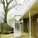 garden picture with a tree and a white spiral stair leading to a walkway