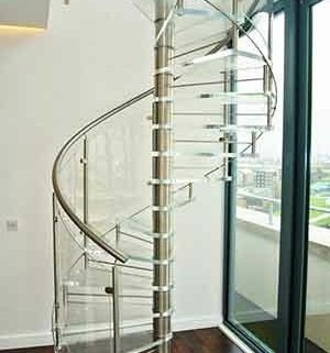 living space with acrylic spiral staircase, dark flooring and white wall behind