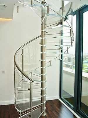 living space with acrylic spiral staircase, dark flooring and white wall behind