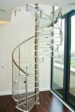 living space with acrylic spiral staircase, dark flooring and white wall behind