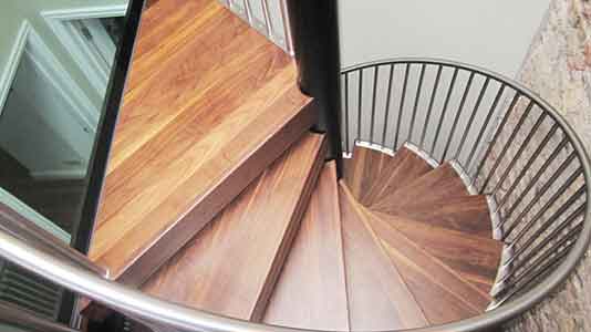 spiral stair with walnut steps with a glass platform above