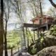 elevated log cabin in the woods with access from a spiral staircase