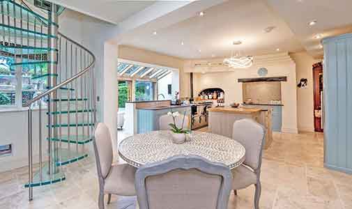 living space with table to centre, kitchen to background and glass spiral to left of picture