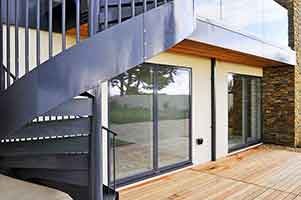 outside spiral staircase dark grey in foreground wooden decking behind
