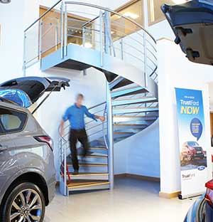 man walking down a spiral staircase with cars in foreground