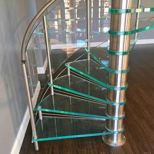 close up on glass treads on a spiral staircase. Dark wooden floor below