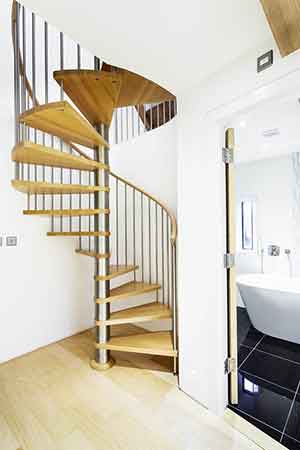 spiral stair set in front of a curved wall with bathroom to right