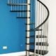 stainless steel and black spiral staircase with a bright blue wall behind