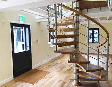 open looking oak and stainless spiral stair in an office setting