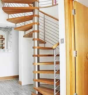 oak spiral stair in a house with a tiled floor and curved wall behind