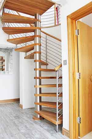 oak spiral stair in a house with a tiled floor and curved wall behind