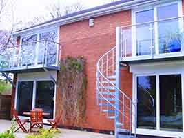 two balconies with glass panels to rear of house with red brick