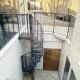 external spiral stair grey in a lightwell with white walls surrounding