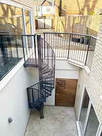external spiral stair grey in a lightwell with white walls surrounding