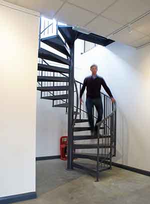 dark grey spiral stair with a man walking down