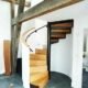 oak spiral stair leadnign to a mezzanine level. White walls and tiled floor
