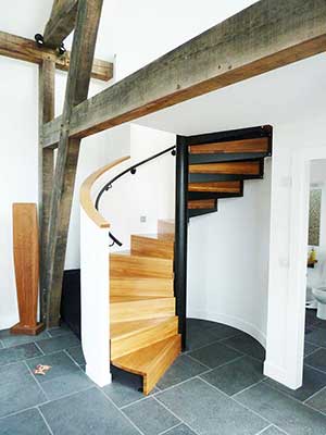 oak spiral stair leadnign to a mezzanine level. White walls and tiled floor