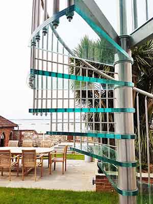 glass and stainless spiral stair to front and garden and sea behind