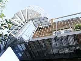 view from below of external balcony with spiral stair and house behind