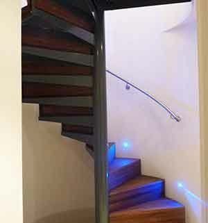 spiral stair with walnut steps and a curved wall with handrail mounted