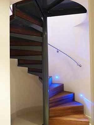 spiral stair with walnut steps and a curved wall with handrail mounted
