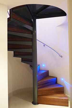 spiral stair with walnut steps and a curved wall with handrail mounted