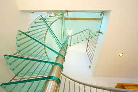 view looking up at a glass step on a spiral staircase in a house