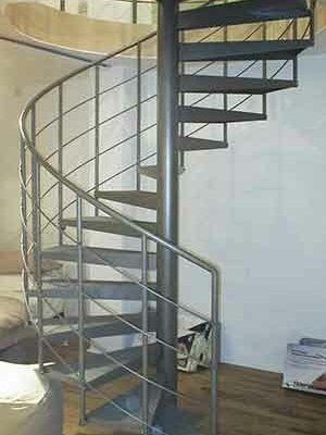 light grey steel spiral staircase in front of a wall