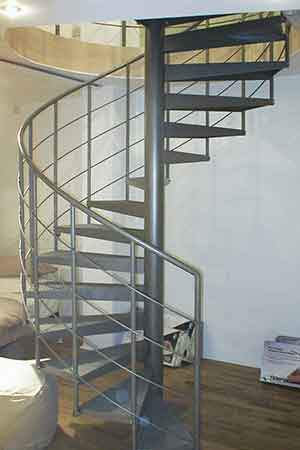 light grey steel spiral staircase in front of a wall