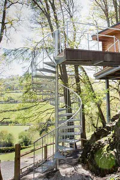 outdoor woodland with large spiral staircase leading upto a walkway