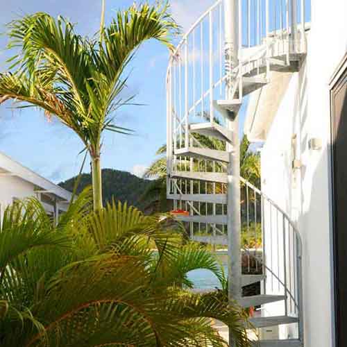 tropical garden with spiral staircase and palm trees