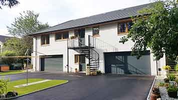 external front shot of a house with white render and tarmac drive and sky above