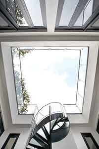 looking up at the sky from a courtyard in a house surrounded by glass balustrade