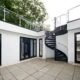 outdoor courtyard with patio tiles, a large dark grey spiral stair
