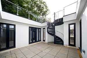 outdoor courtyard with patio tiles, a large dark grey spiral stair