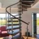 wooden spiral stair with glass panels and dark timber handrail. huge window behind