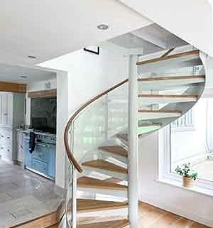 steel, wood and glass spiral stair in a house, kitch seen behind