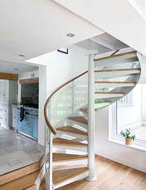 steel, wood and glass spiral stair in a house, kitch seen behind