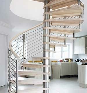 spiral stair in light wood with kitchen on show behind and a window