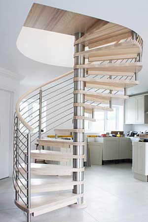 spiral stair in light wood with kitchen on show behind and a window