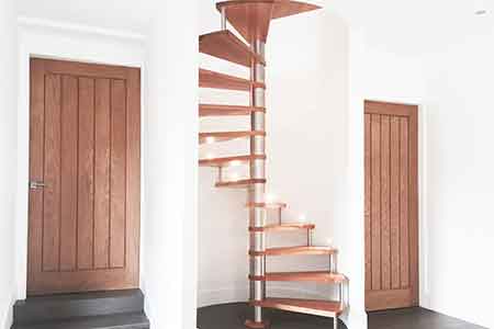 curved wall behind a spiral stair and two oak doors