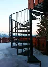 the alps in the background and a black spiral stair in the foreground