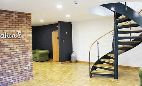 modern spiral stair in an office setting with a wall and a wooden floor on show