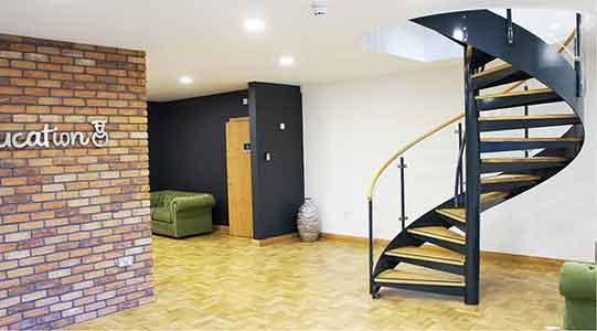 modern spiral stair in an office setting with a wall and a wooden floor on show