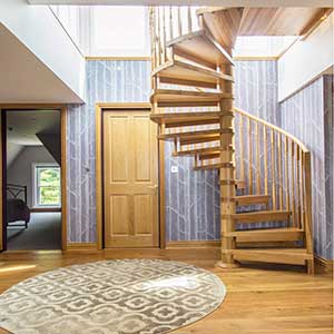 oak spiral stair in a house in front of a wallpapered wall