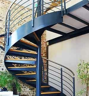 green plants behind a large steel spiral steel with wooden steps
