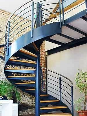 green plants behind a large steel spiral steel with wooden steps