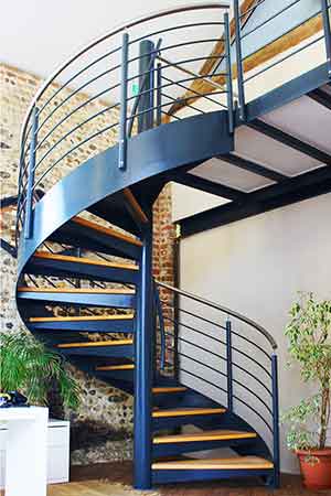 green plants behind a large steel spiral steel with wooden steps